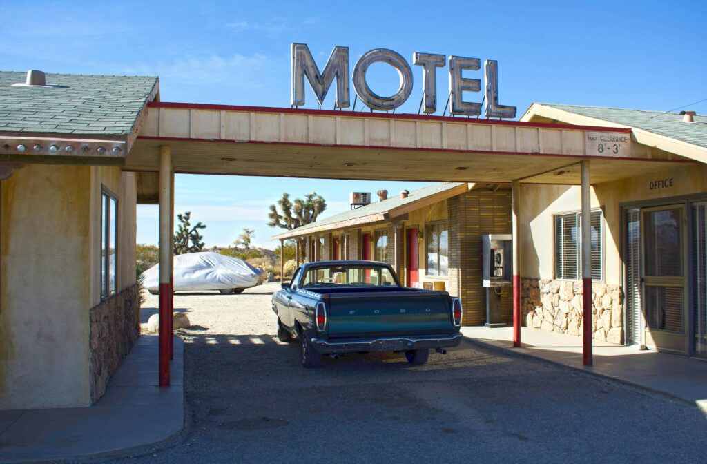 Image Shows motel and customer park a car under the motel roof